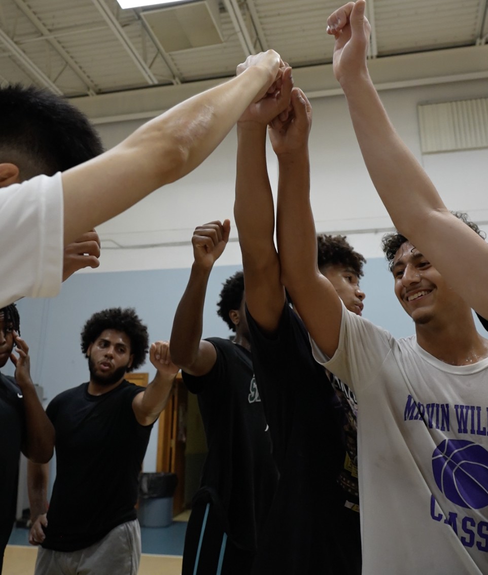 Basketball players in a team huddle with hands together